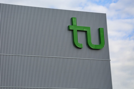 Das große Logo der TU an einem Gebäude.