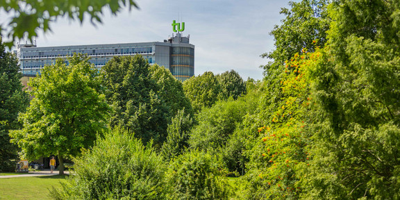 Das Mathematikgebäude mit grünen Bäumen im Vordergrund.